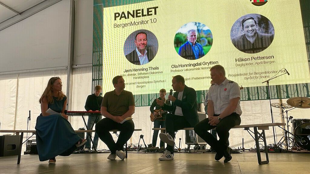 Panelsamtale på scenen under VM-gudstjenesten i Bergen, med lerret som viser panelet for BergenMonitor 1.0